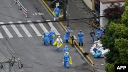 Health workers in protective suits walk along a street during a COVID-19 lockdown in the Jing'an district of Shanghai, China, April 24, 2022.