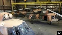 FILE - Damaged Afghan military helicopters are parked inside the Hamid Karzai International Airport after the Taliban's takeover, in Kabul, Sept. 5, 2021. 