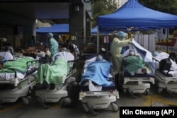 Patients lie on hospital beds as they wait at a temporary makeshift treatment area outside Caritas Medical Centre in Hong Kong on February 18, 2022, as Hong Kong's hospitals reached 90% capacity on Thursday and quarantine facilities were at their limit, authorities said. (AP Photo/Kin Cheung, File)