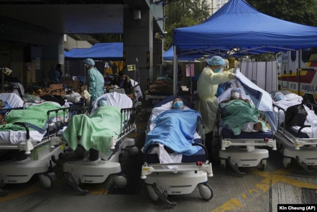 Patients lie on hospital beds as they wait at a temporary makeshift treatment area outside Caritas Medical Centre in Hong Kong on February 18, 2022, as Hong Kong's hospitals reached 90% capacity on Thursday and quarantine facilities were at their limit, authorities said. (AP Photo/Kin Cheung, File)