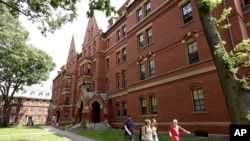 FILE — People walk along a sidewalk on the campus of Harvard University, in Cambridge, Mass., July 16, 2019. Harvard President Lawrence Bacow announced April 26, 2022 that the university is committing $100 million to study its ties to slavery. 