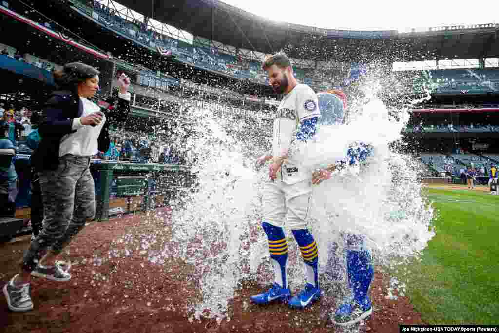 Seattle Mariners right fielder Jesse Winker (27) is doused with a water cooler during a postgame interview after hitting a walk-off RBI-single against the Kansas City Royals during the twelfth inning at T-Mobile Park, April 24, 2022.