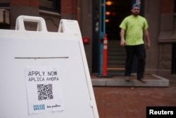 An "Apply Now" sign stands outside a bar on Newbury Street in Boston, Massachusetts, April 27, 2022.