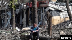 ARCHIVO - Un hombre permanece sentado en un patio cerca de un edificio dañado durante el conflicto entre Ucrania y Rusia en la ciudad portuaria sureña de Mariúpol, Ucrania, el 25 de abril de 2022.