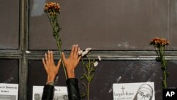 FILE - A woman places a flower outside the Attorney General's office in protest after Debanhi Escobar's decomposing body was found in a water tank in Mexico City, April 22, 2022.