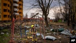 A firefighter sits on a swing next to a building destroyed by a Russian bomb in Chernihiv, Ukraine.