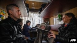 Evgueni Tichtchenko, Tetiana Komissarova and their children sit in an evacuation train to Lviv the day after arriving with a humanitarian convoy from the besieged city of Mariupol, at a railway station in Zaporijjia, southeastern Ukraine, April 22, 2022.