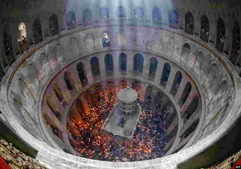 Orthodox Christians gather with lit candles around the Edicule, traditionally believed to be the burial site of Jesus Christ, during the Holy Fire ceremony at Jerusalem's Holy Sepulchre church, April 23, 2022. 
