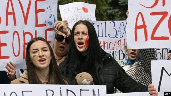 Activists hold banners during a meeting to urge foreign leaders and international organizations to help provide humanitarian corridors for evacuation of civilians and Ukrainian servicemen from Mariupol, in central Kyiv, April 27, 2022, amid Russia's invasion of Ukraine.