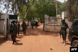 FILE - Nigerian soldiers and police officers stand at the entrance of a forestry college in Kaduna state, on March 12, 2021, after a kidnap gang stormed the school.