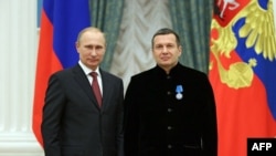 FILE - Russian President Vladimir Putin poses with TV anchor Vladimir Solovyov during an awards ceremony at the Kremlin in Moscow, Dec. 25, 2013.