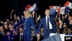 French President and La Republique en Marche (LREM) party candidate for re-election Emmanuel Macron (R) holds his fist in the air as he holds Brigitte Macron's hand after his victory in France's presidential election, at the Champ de Mars in Paris, April 24, 2022.