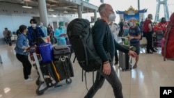 FILE - Tourists arrive at Suvarnabhumi International Airport in Bangkok, Thailand, Monday, Nov. 1, 2021. Thailand announced Friday, April 22, 2022, that visitors who are fully vaccinated against the coronavirus will no longer need to undergo any test or q