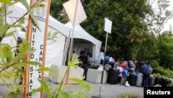 A line of asylum seekers wait to enter into Canada from Roxham Road in Champlain, New York, August 7, 2017.