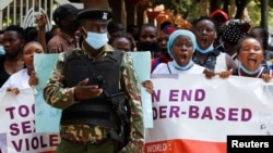 FILE - A policeman stands guard while members of the civil society chant slogans as they demonstrate against gender-based violence to mark International Women's Day in downtown Nairobi, Kenya, March 8, 2022. 