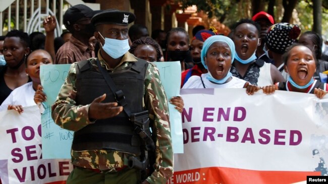 FILE - A policeman stands guard while members of the civil society chant slogans as they demonstrate against gender-based violence to mark International Women's Day in downtown Nairobi, Kenya, March 8, 2022.