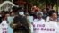 FILE - A policeman stands guard while members of the civil society chant slogans as they demonstrate against gender-based violence to mark International Women's Day in downtown Nairobi, Kenya, March 8, 2022. 