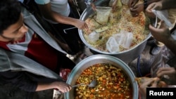 Para sukarelawan menyiapkan makanan untuk dibagikan di dapur amal selama bulan suci Ramadan di Sanaa, Yaman, 18 April 2022. (REUTERS/Khaled Abdullah)