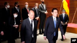 German Chancellor Olaf Scholz, left, and his Japanese counterpart Fumio Kishida walk together after viewing an honor guard ahead of their bilateral meeting at the prime minister's office in Tokyo, April 28, 2022. 