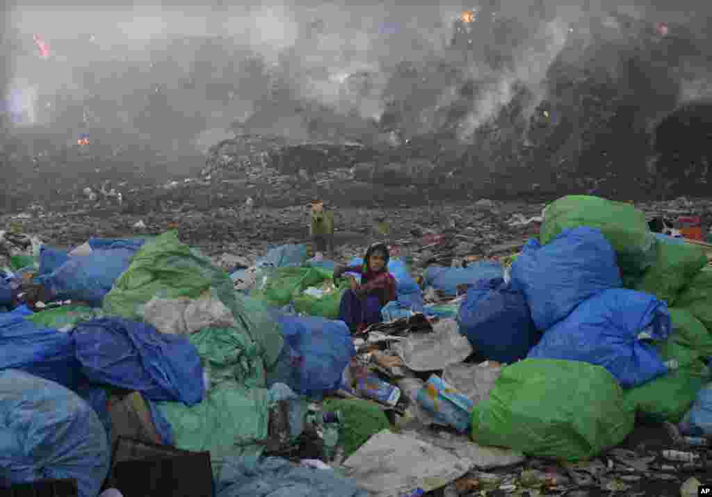 A collector picks up things during a fire at the Bhalswa landfill in New Delhi, India.