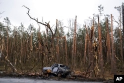 The gutted remains of a car in front of damaged trees are pictured after a battle between Russia and Ukrainian forces on the outskirts of Chernihiv, Ukraine, April 22, 2022.