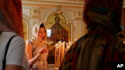 A Russian-speaking expat lights a candle at the Christian Orthodox Church in Sharjah, United Arab Emirates, April 24, 2022. Hundreds of Russians and Ukrainians alike crowded into the only Russian Orthodox Church on the Arabian Peninsula on Sunday to celebrate Easter.