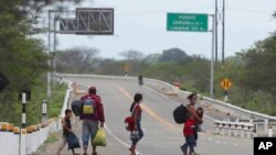 Migrantes venezolanos caminan por la Carretera Panamericana después de cruzar la frontera ecuatoriana hacia Tumbes, Perú, el sábado 30 de enero de 2021.