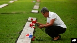 Una mujer coloca flores en la tumba de una persona que murió durante la invasión militar estadounidense de 1989 que derrocó al dictador panameño Manuel Noriega, en el 30 aniversario de la invasión en Ciudad de Panamá, el viernes 20 de diciembre de 2019.