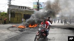 Un taxista en motocicleta traslada a clientes cerca de una protesta contra la creciente violencia, el martes 29 de marzo de 2022, en Puerto Príncipe, Haití. 