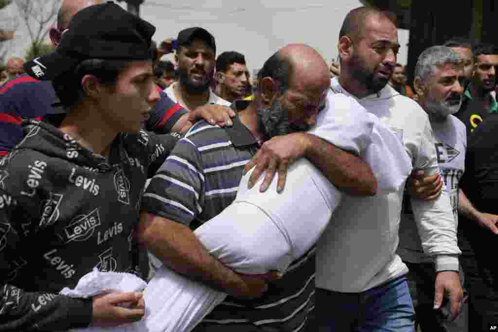 A man cries as he carries the body of a young girl during the funeral procession for seven people killed when a boat filled with migrants sunk over the weekend as the Lebanese navy tried to force it back to shore, in Tripoli, north Lebanon.