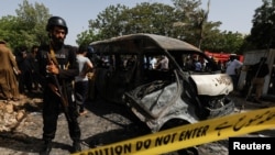 A police officer stands guard near a passenger van, cordoned after a blast at the entrance of the Confucius Institute University of Karachi, Pakistan, Apr. 26, 2022. 