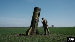 A Ukrainian serviceman looks at a Russian ballistic missile's booster stage that fell in a field in Bohodarove, eastern Ukraine, on April 25, 2022, amid the Russian invasion of Ukraine. 