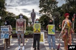 Aksi para aktivis lingkungan untuk menandai 'Hari Bumi' di Surabaya, 22 April 2022, dengan memajang plakat di samping manekin berpakaian sampah plastik. (JUNI KRISWANTO / AFP)