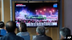 People watch a TV screen showing a news report about North Korea's military parade, at a train station in Seoul, South Korea, April 26, 2022.
