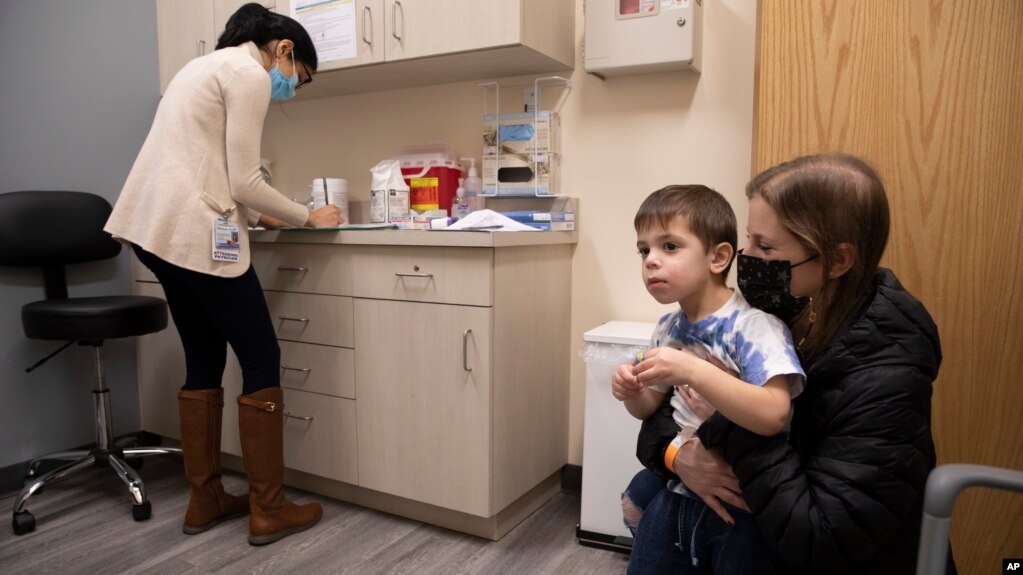 FILE - Ilana Diener holds her son, Hudson, 3, during an appointment for a Moderna COVID-19 vaccine trial in Commack, N.Y. on Nov. 30, 2021. Moderna asked U.S. regulators to authorize low doses of its COVID-19 vaccine for children under 6. (AP Photo/Emma H. Tobin, File)