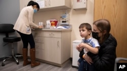 FILE - Ilana Diener holds her son, Hudson, 3, during an appointment for a Moderna COVID-19 vaccine trial in Commack, N.Y. on Nov. 30, 2021. Moderna asked U.S. regulators to authorize low doses of its COVID-19 vaccine for children under 6. (AP Photo/Emma H. Tobin, File)