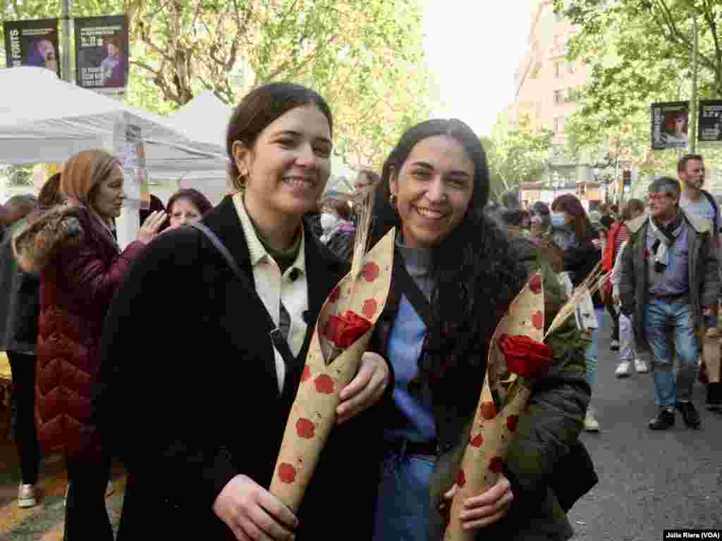 Dos jóvenes posan con rosas en el centro de Barcelona.