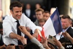 French President and centrist La Republique en Marche (LREM) party candidate for re-election Emmanuel Macron shakes hands with supporters a rally on the last day of campaigning, in Figeac, southern France, April 22, 2022.