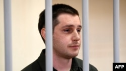 FILE - U.S. ex-marine Trevor Reed, charged with attacking police, stands inside a defendants' cage during a court hearing in Moscow, March 11, 2020. 