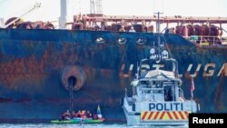 Policijski brod pored gumenog čamca aktivista Grinpisa koji blokiraju ruski tanker "Ust Luga" nedozvoljavajući mu da istovari rusku naftu u norvešku luku, u znak protesta protiv ruske invazije na Ukrajinu, u blizini Asgardstranda, Norveška, 25. aprila 2022.