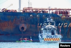 Sebuah kapal polisi berlayar di dekat anggota Greenpeace yang menghalangi kapal tanker 'Ust Luga' mengirimkan minyak Rusia ke Norwegia dekat Asgardstrand, Norwegia, 25 April 2022. (Foto: via Reuters)