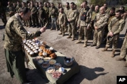 A military Orthodox priest blesses traditional food during the Easter celebration at the frontline position of 128 brigade of Ukrainian army near Zaporizhzhia, Ukraine, April 24, 2022.