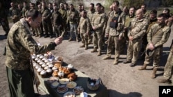 Vojni pravoslavni sveštenik blagosilja tradicionalnu hranu tokom proslave Uskrsa na frontu 128. brigade ukrajinske vojske u blizini Zaporožja, Ukrajina, 24. aprila 2022.