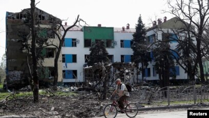 A man rides a bicycle near a building heavily damaged during Ukraine-Russia conflict in the southern port city of Mariupol, Ukraine April 25, 2022.