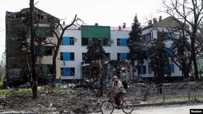 A man rides a bicycle near a building heavily damaged during Ukraine-Russia conflict in the southern port city of Mariupol, Ukraine April 25, 2022.