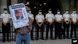 ARCHIVO. Un manifestante sostiene un cartel con un retrato del presidente guatemalteco Alejandro Giammattei frente al Palacio Nacional mientras la gente asiste a una manifestación en apoyo del fiscal anticorrupción Juan Francisco Sandoval, en Ciudad de Guatemala.