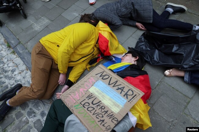 Climate activists perform at a protest in front of the German Embassy on Earth Day to call for an immediate embargo on Russian oil and gas, in Brussels, Belgium, April 22, 2022. (REUTERS/Johanna Geron)