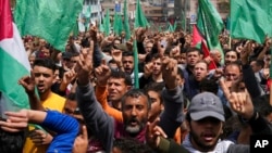 Hamas supporters wave green Islamic flags while raise their hands up and chant slogans during a rally in solidarity with Palestinian residents of the West Bank and Jerusalem, at the main road of Jebaliya refugee camp, northern Gaza Strip, April 22, 2022. 