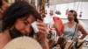 زنان در یک بازار دستفروشی در شهر مادرید اسپانیا در هوای داغ ماه اوت ۲۰۲۱ خود را با بادبزن دستی باد می‌زنند. 