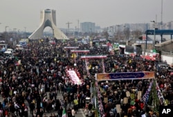FILE - Iranians attend an annual rally commemorating the anniversary of the 1979 revolution, on Azadi (Freedom) Street, while the Azadi tower is seen at rear left, in Tehran, Iran, Feb. 11, 2014.
